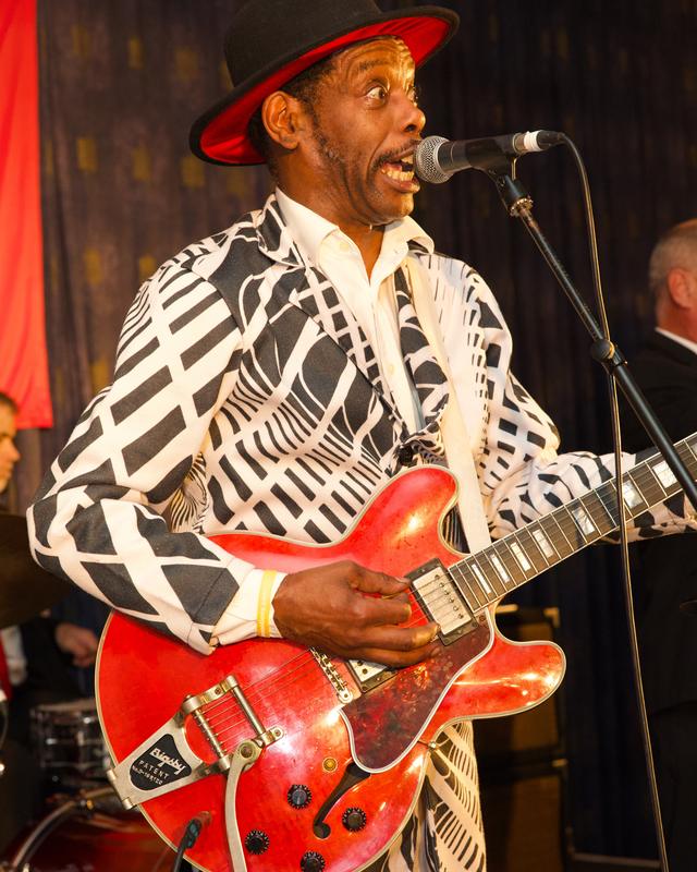 A guitarist in a red hat playing a red guitar